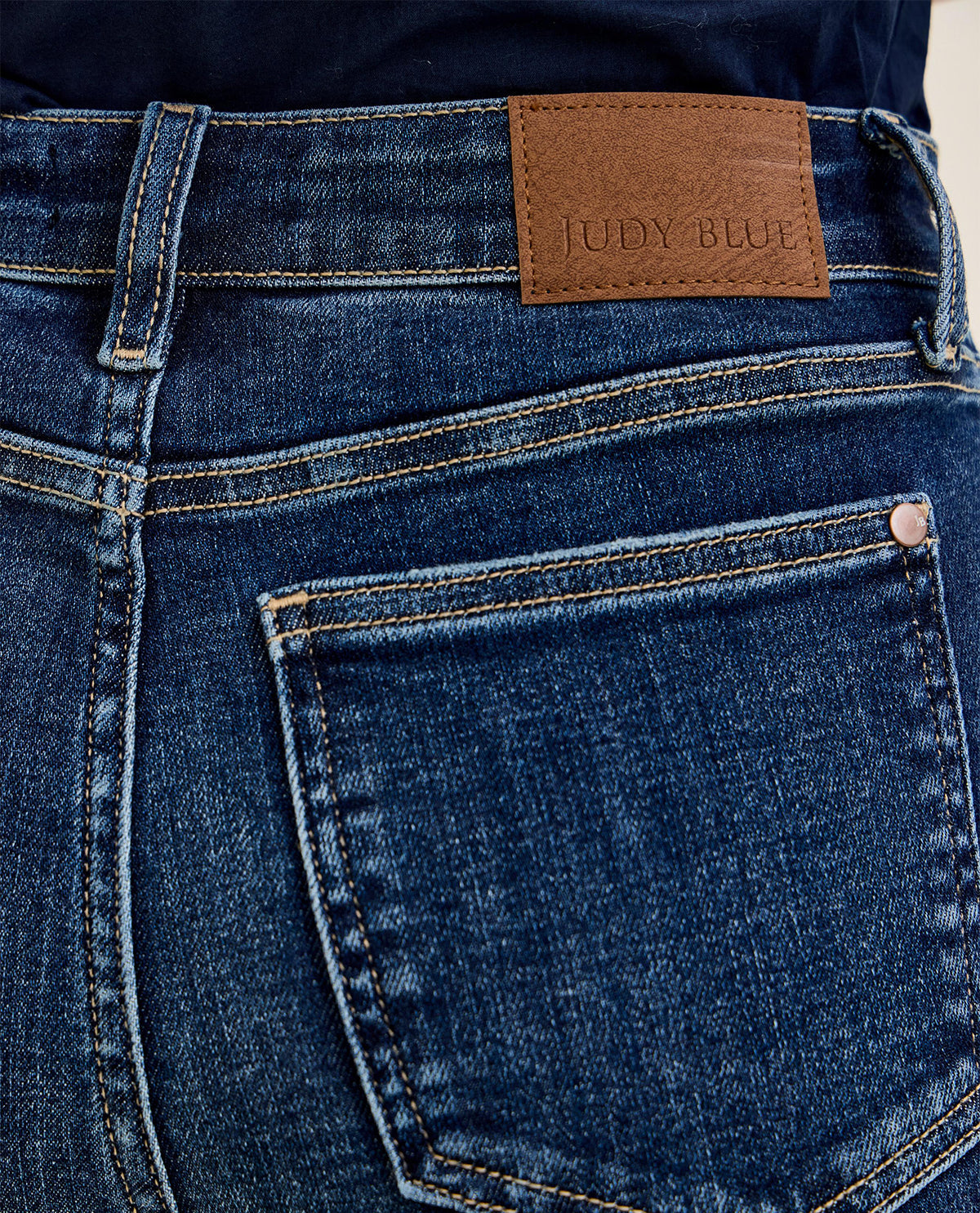 Close-up of blue jeans with a brown leather patch displaying 'Judy Blue' brand name.