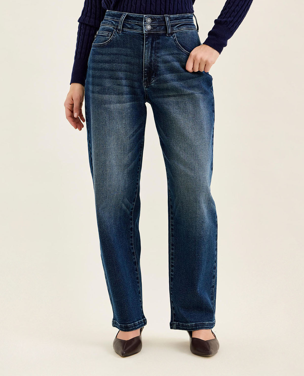 Person wearing blue jeans on a plain background