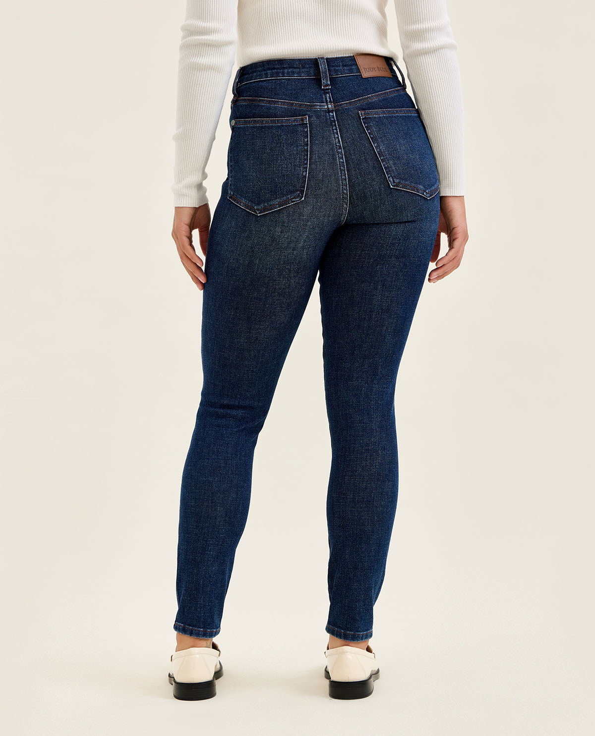 Person wearing dark blue jeans on a white background