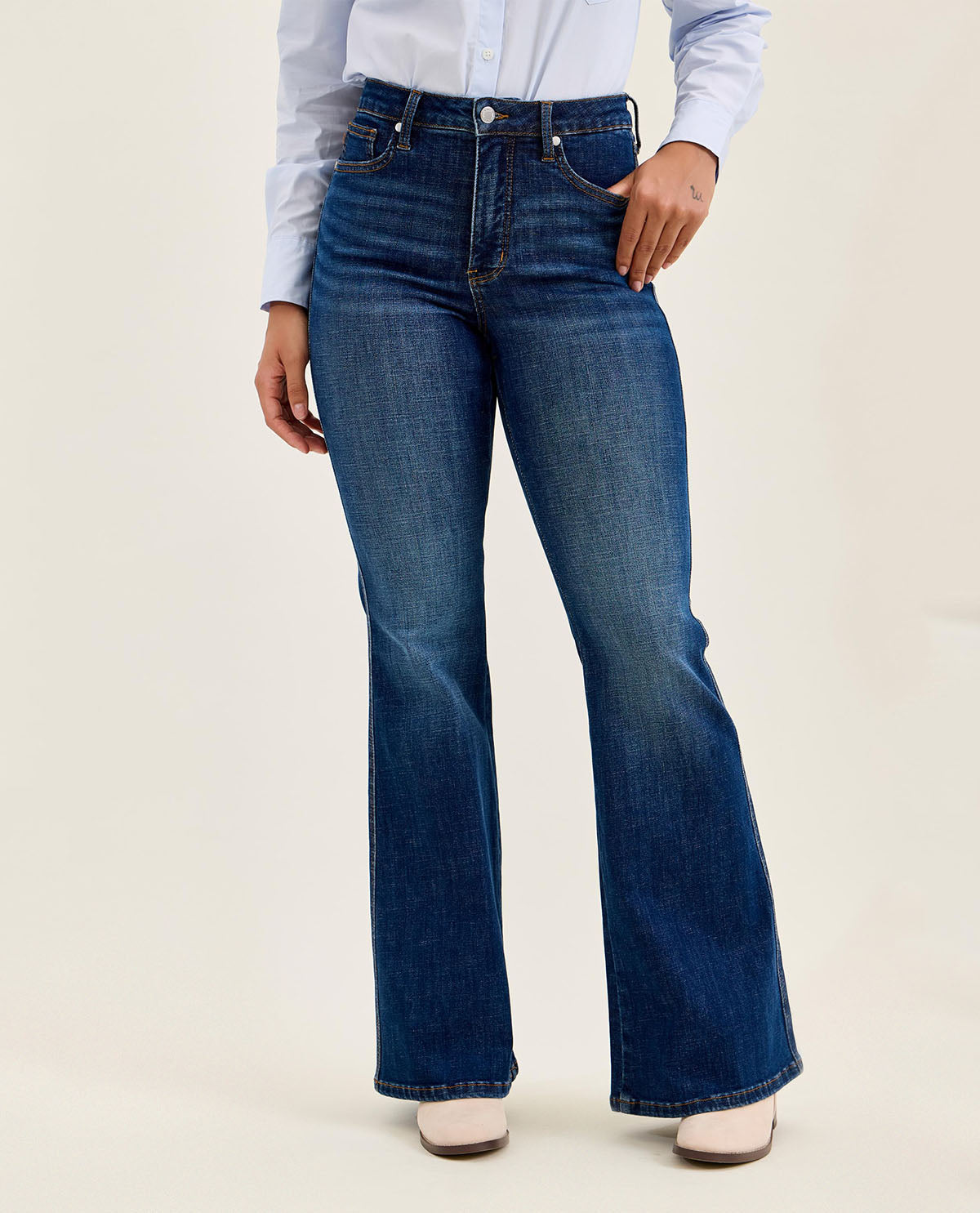 Person wearing blue flared jeans on a plain background