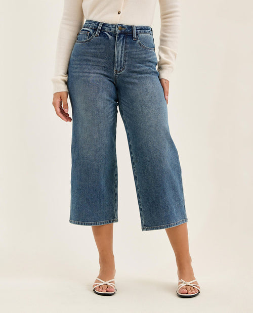 Person wearing blue jeans on a plain background