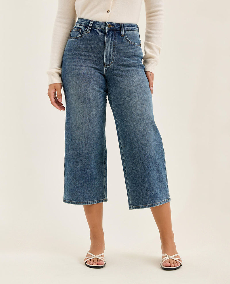 Person wearing blue jeans on a plain background