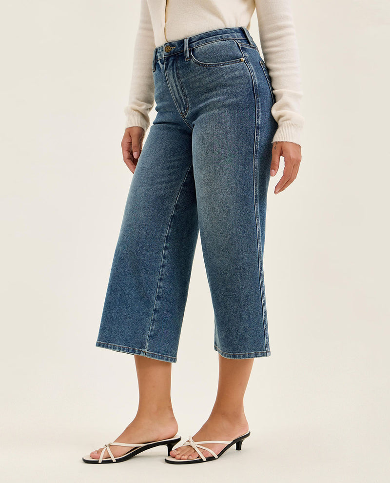 Person wearing blue jeans on a plain background