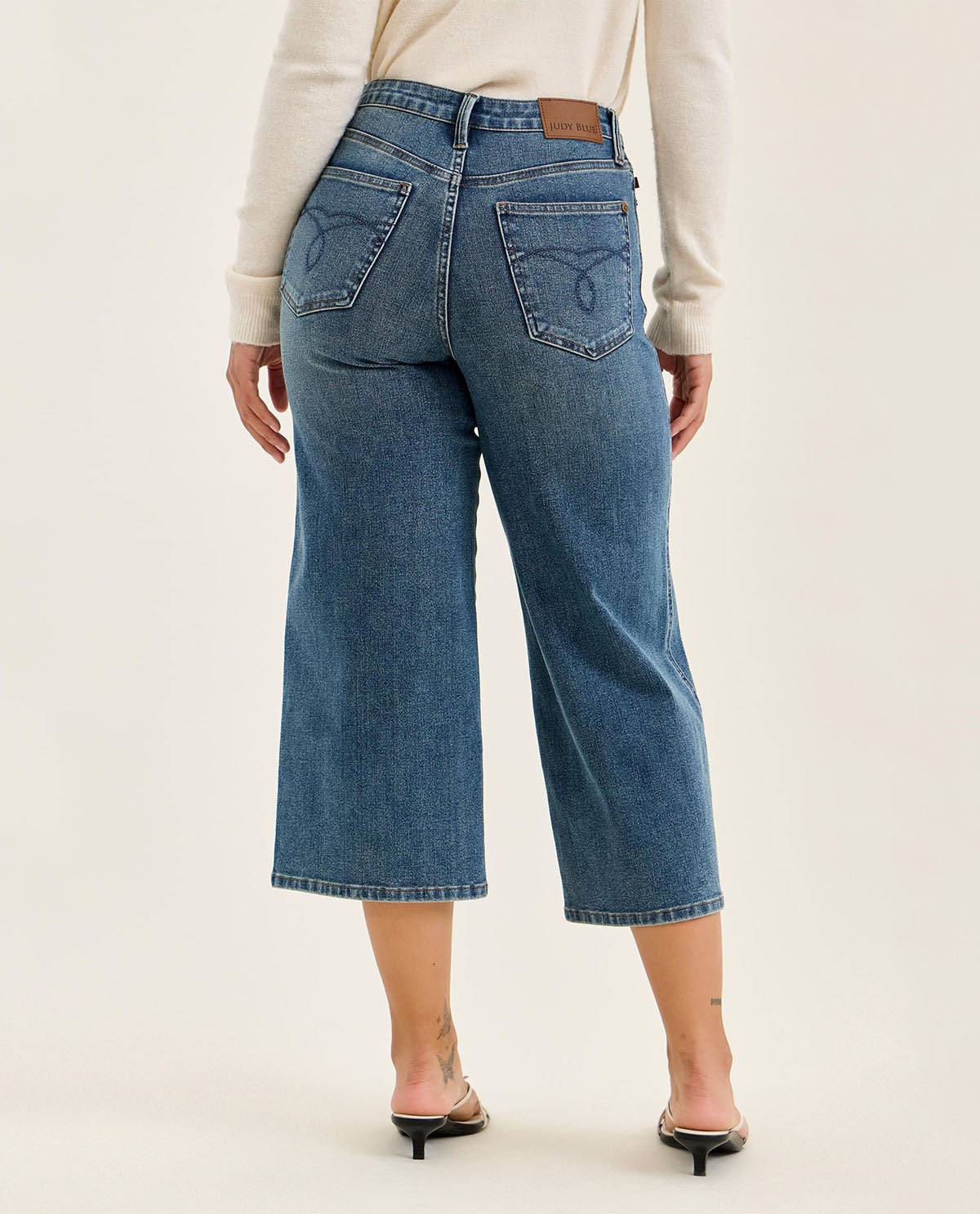 Person wearing blue jeans on a plain background