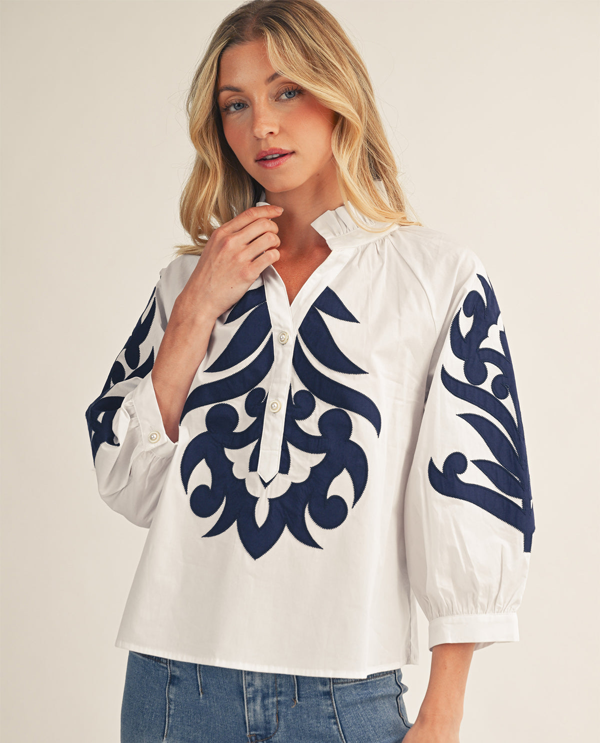 Woman wearing a white blouse with blue floral patterns on a beige background