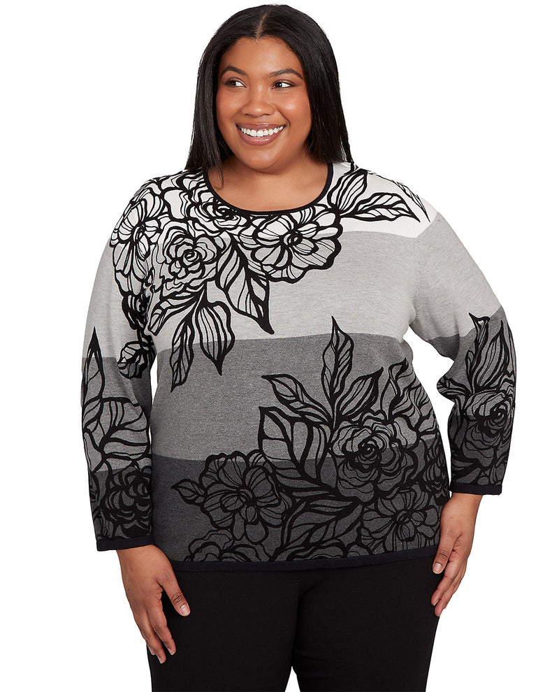 Woman wearing a gray sweater with black floral patterns on a white background