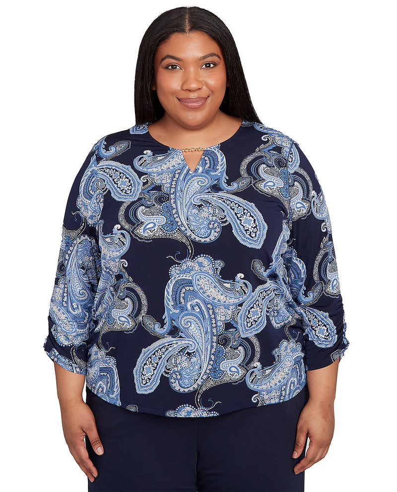 Woman wearing a navy blue blouse with blue paisley pattern on a white background