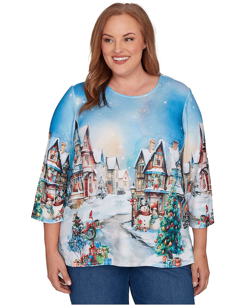 Woman wearing a Christmas-themed sweater with a winter village design.