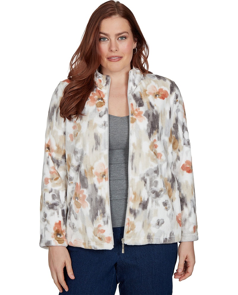 A woman wearing a lightweight zip-front jacket with a watercolor-style floral print in beige, orange, and gray over a gray top and dark blue jeans, photographed against a plain white background.