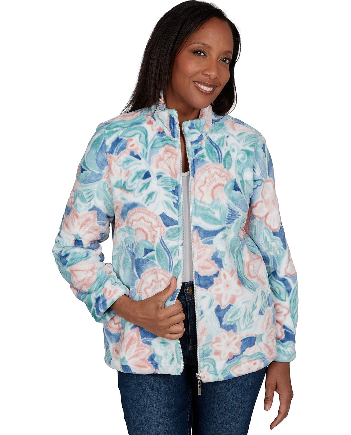 A woman wearing a light blue, pink, and white floral print zip-up jacket, paired with dark blue jeans, against a plain white background.