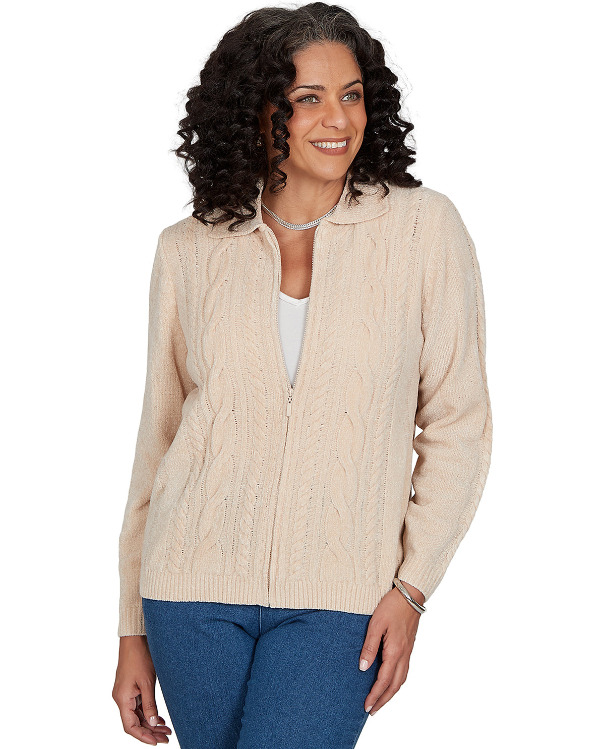 A woman wearing a cream cable-knit zip-up cardigan over a white top and blue jeans, photographed against a plain white background.