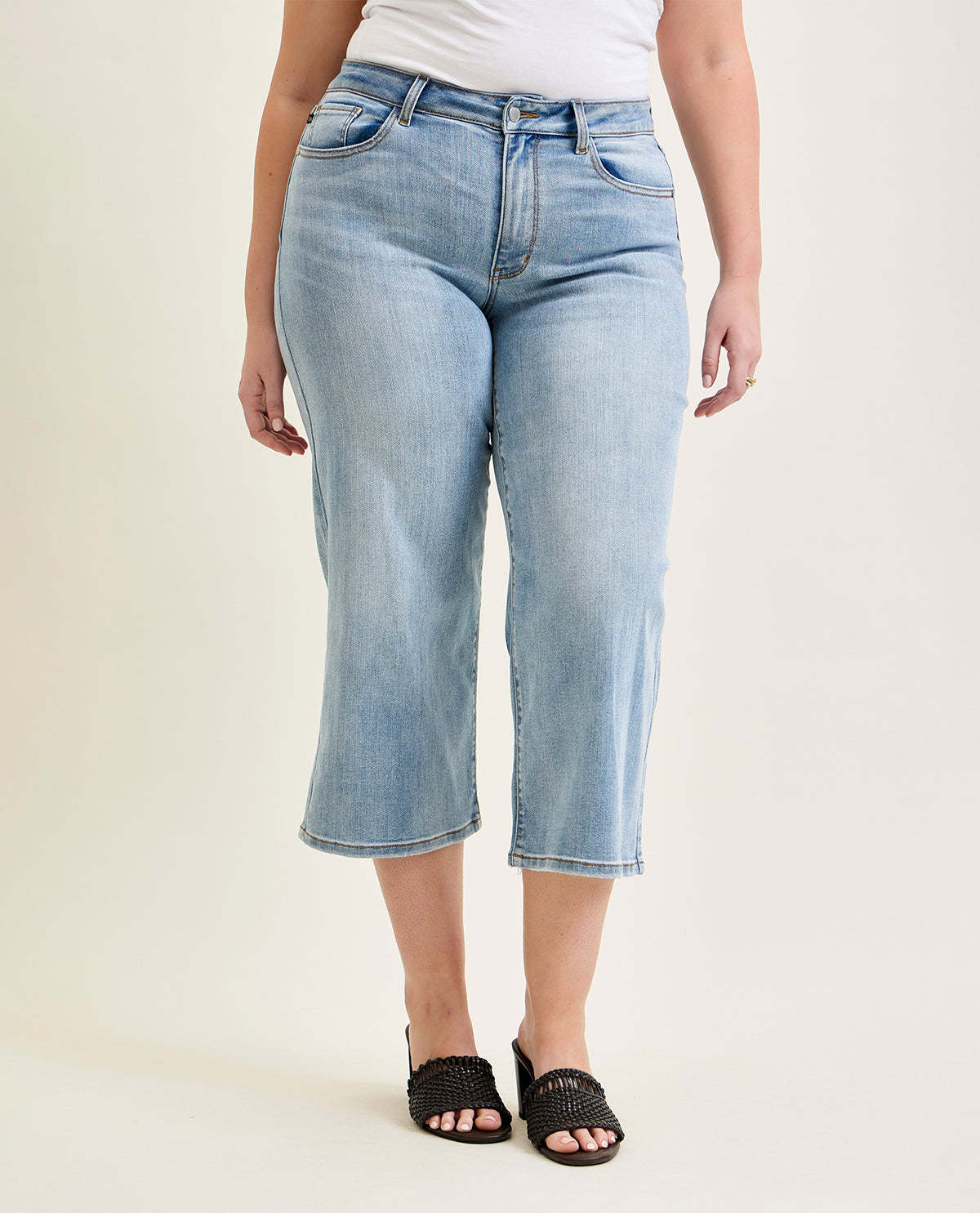 Person wearing light blue jeans on a plain background