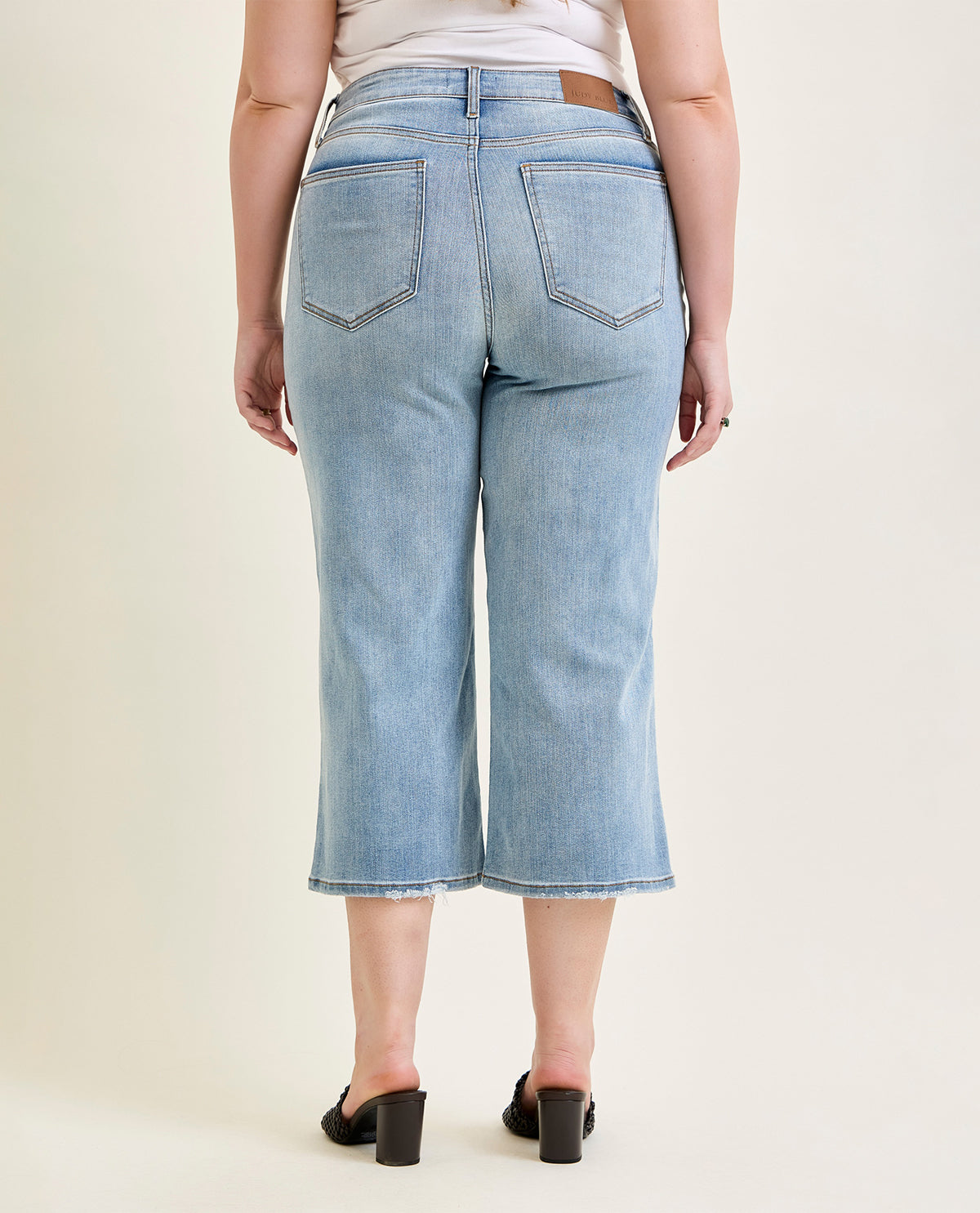 Person wearing light blue denim culottes on a plain background