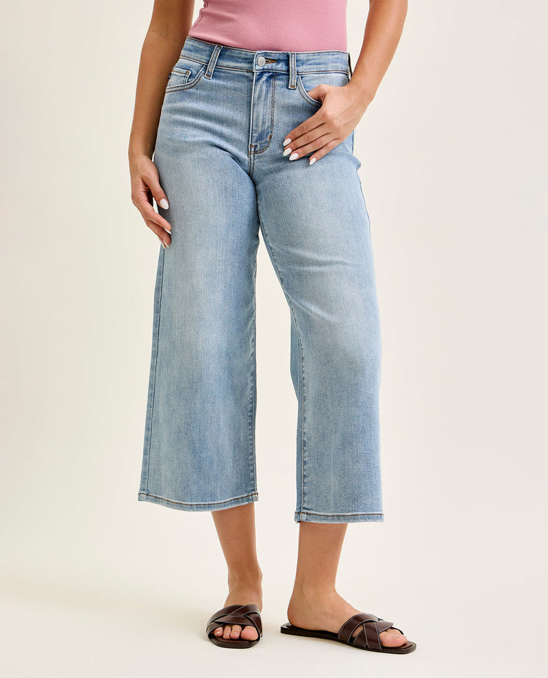 Person wearing light blue wide-leg jeans on a plain background