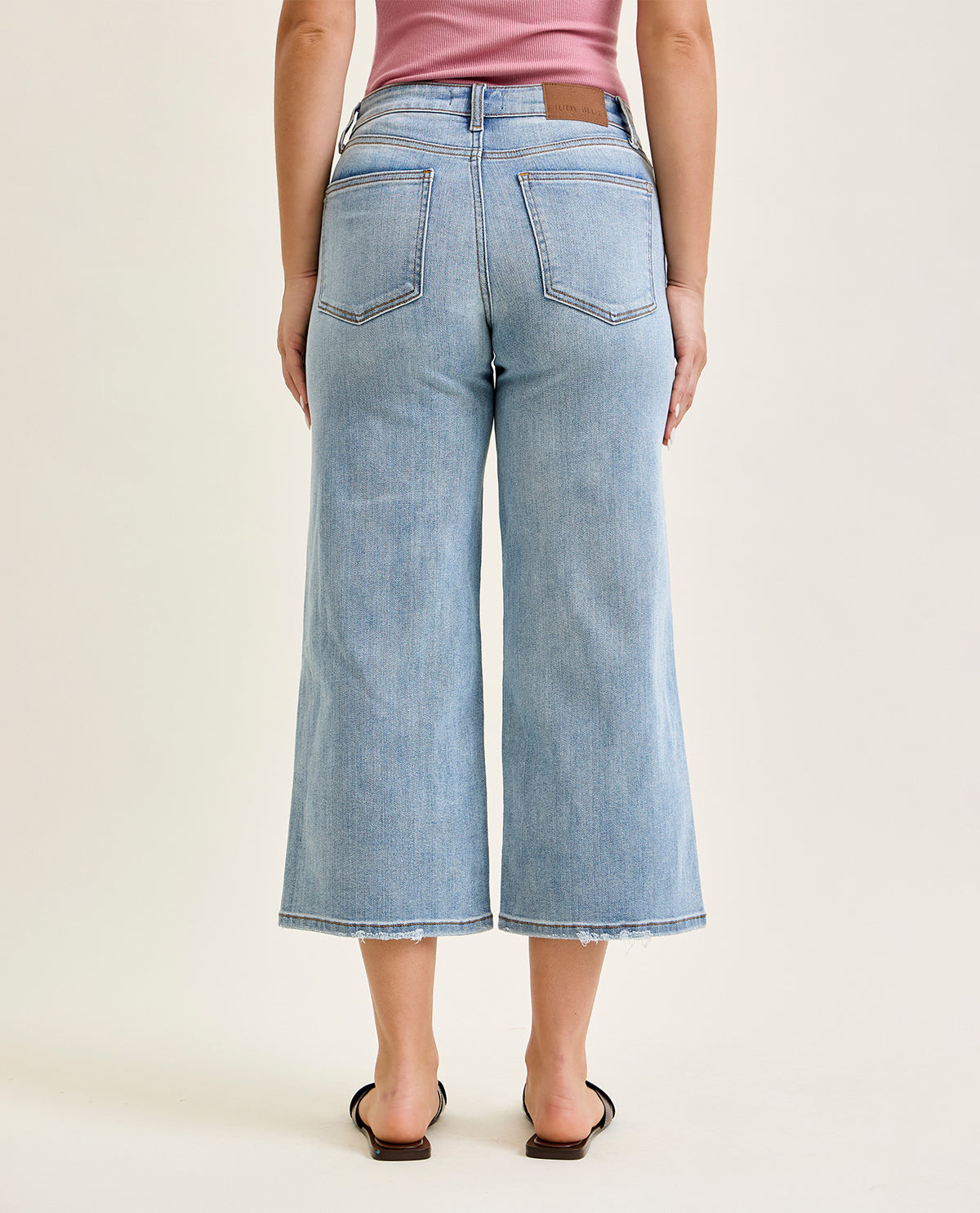 Person wearing light blue wide-leg jeans on a white background