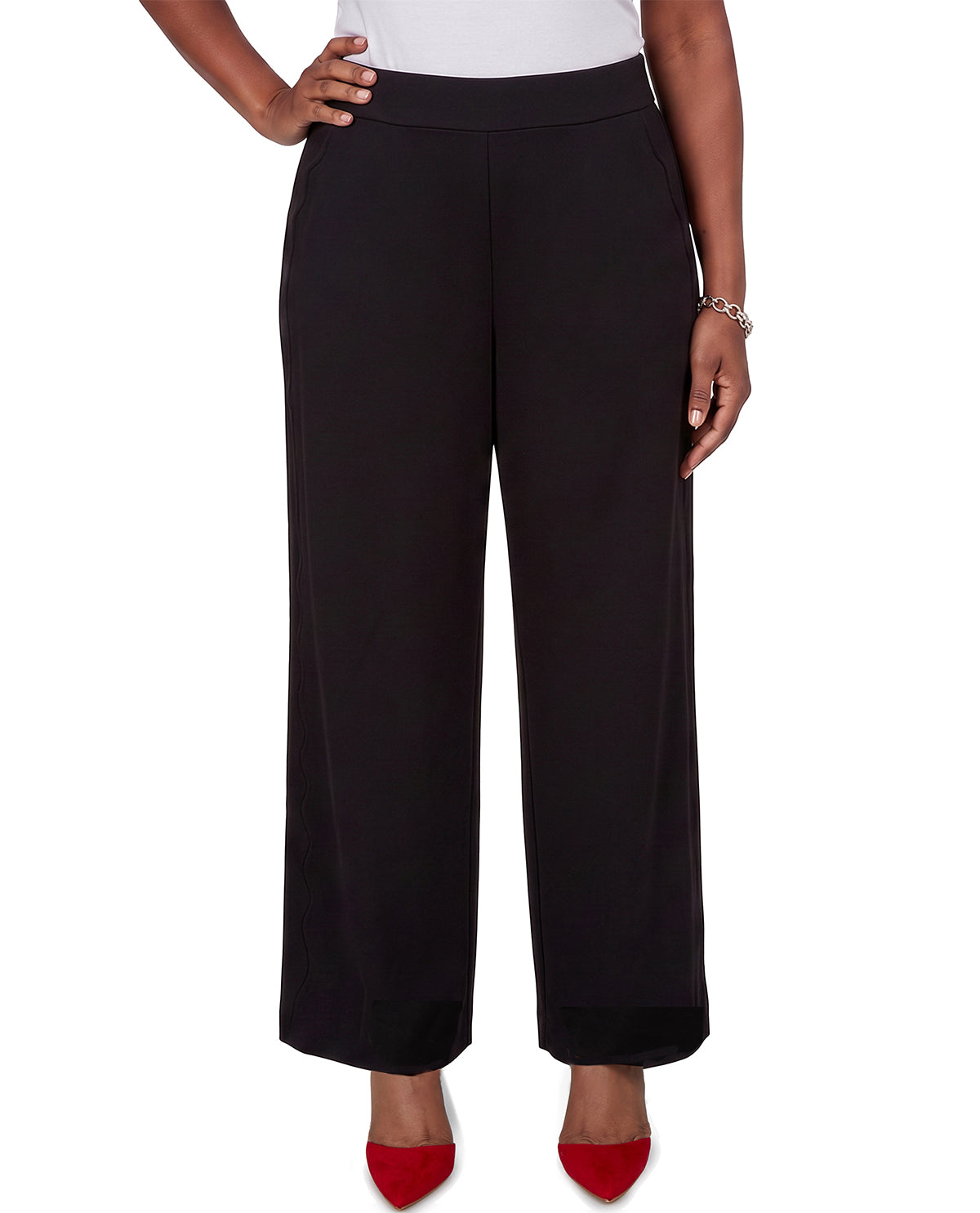 A model wearing black wide-leg cropped trousers with a matching black belt, styled with a white top and red pointed-toe heels against a white background.