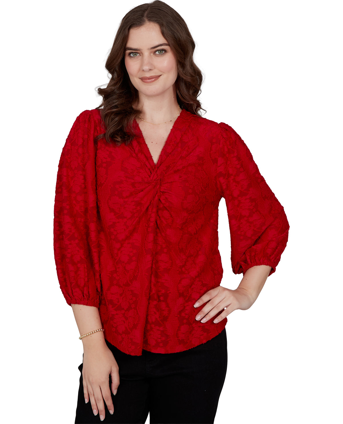 A woman modeling a red textured blouse with a gathered front and puff sleeves, paired with black pants, against a plain white background.