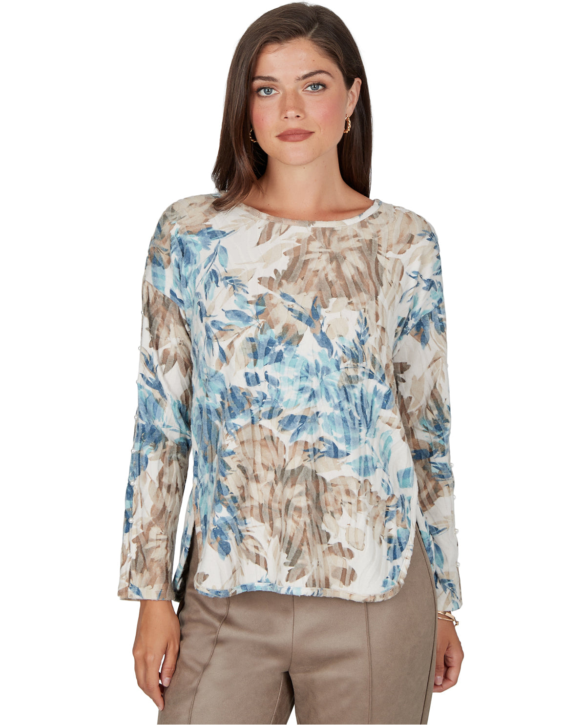 A woman modeling a long-sleeve blouse with a blue, beige, and white abstract floral pattern, paired with khaki pants, against a plain white background.