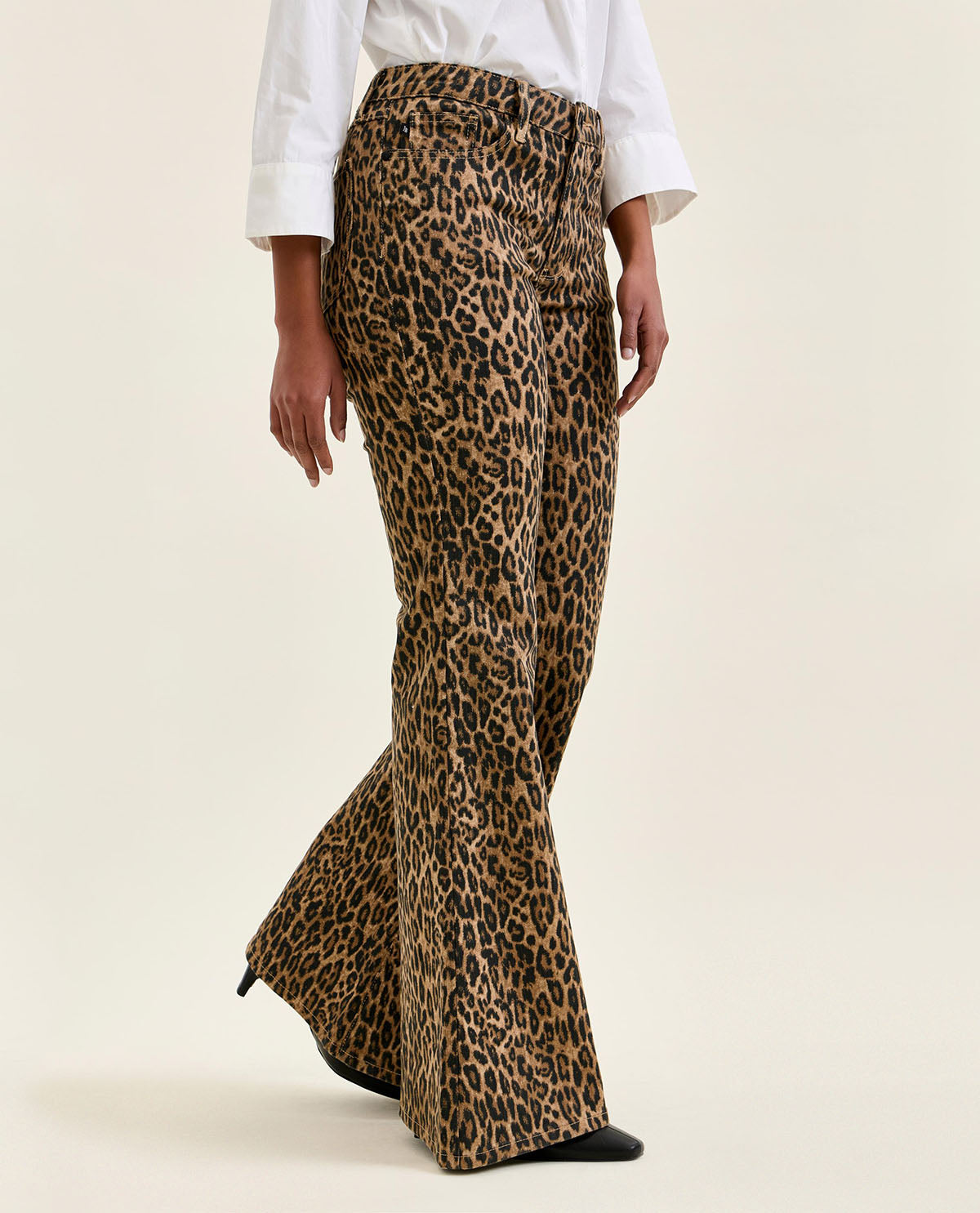 Leopard print flared pants worn by a person on a beige background