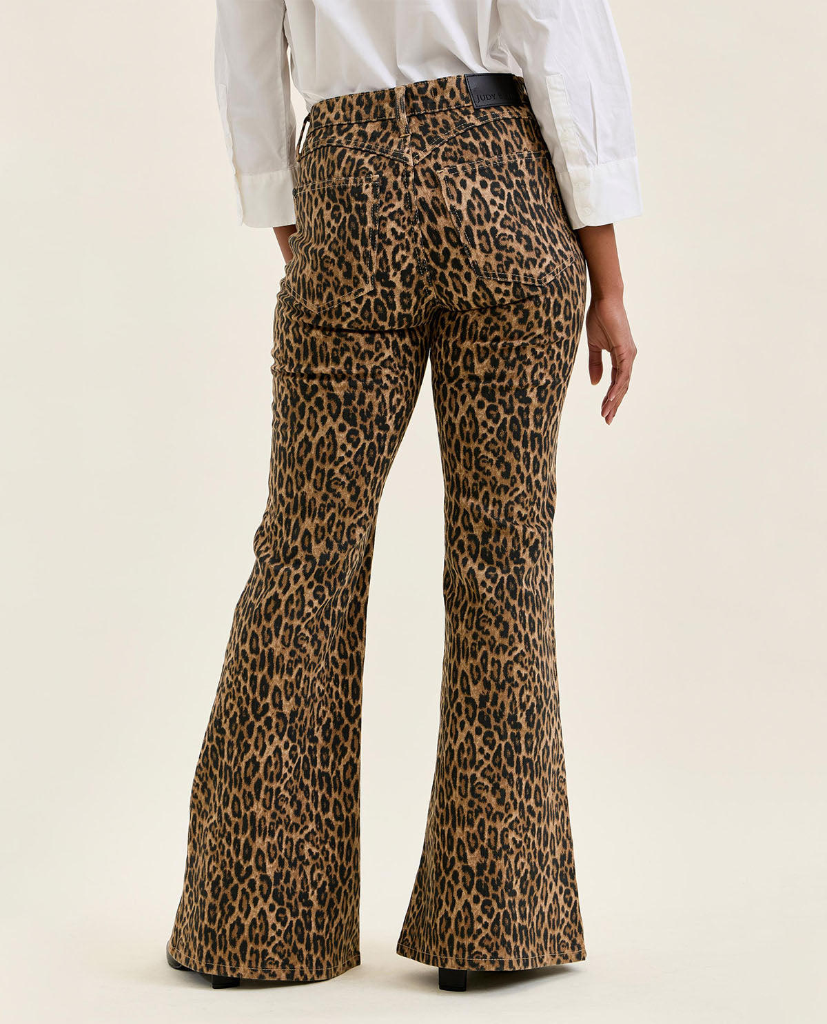 Leopard print flared pants worn by a person on a beige background