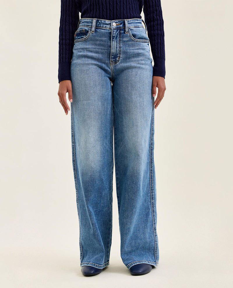 Person wearing blue jeans on a beige background