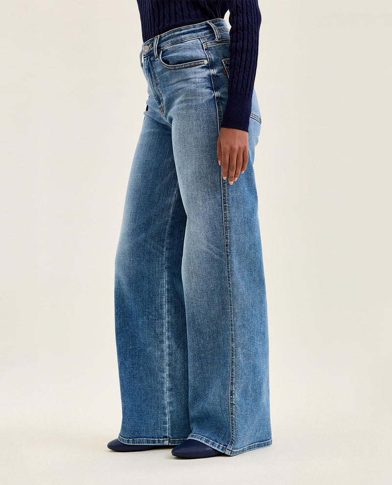 Person wearing blue wide-leg jeans on a white background