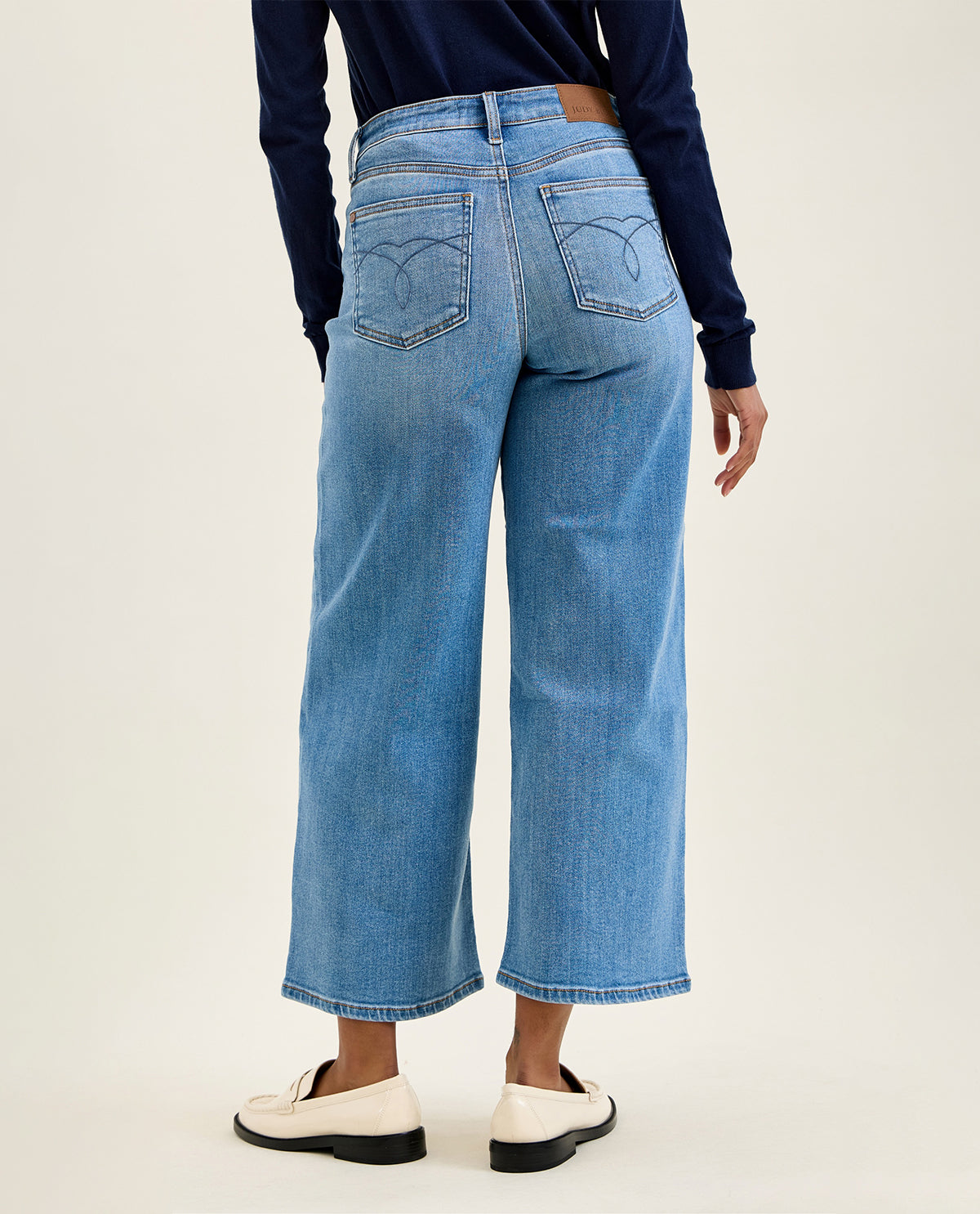 Person wearing blue jeans and a navy long-sleeve shirt on a white background