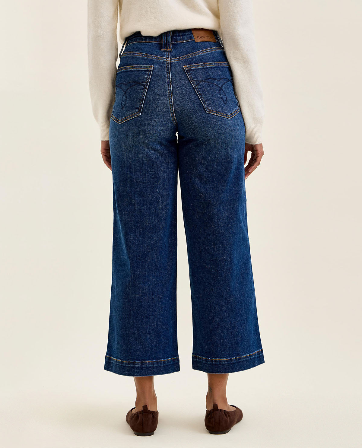 Person wearing blue jeans on a plain background