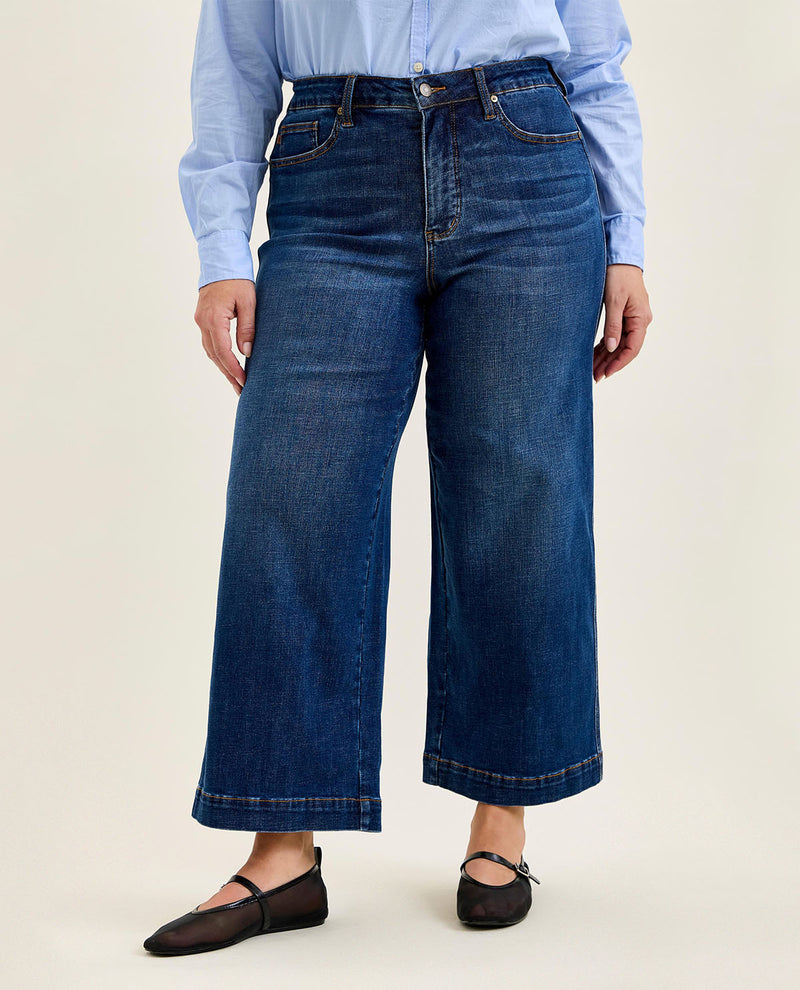 Person wearing blue jeans and a light blue shirt on a beige background