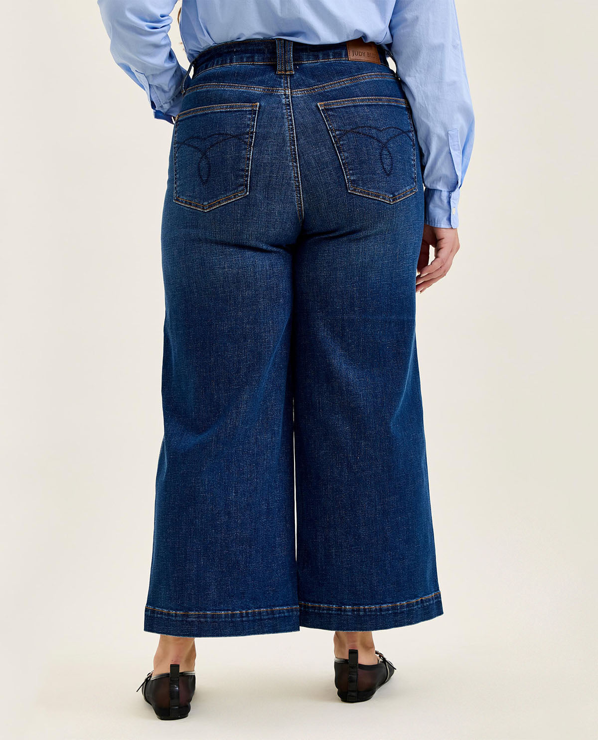 Person wearing blue jeans and a light blue shirt on a white background