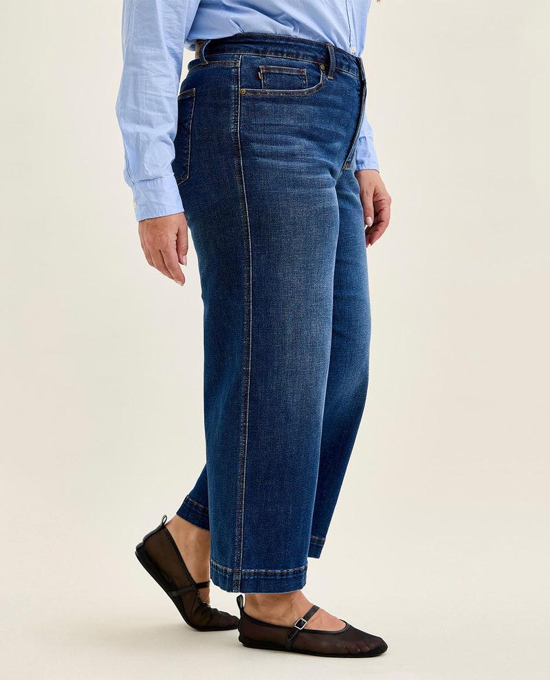 Person wearing blue jeans and a light blue shirt on a beige background