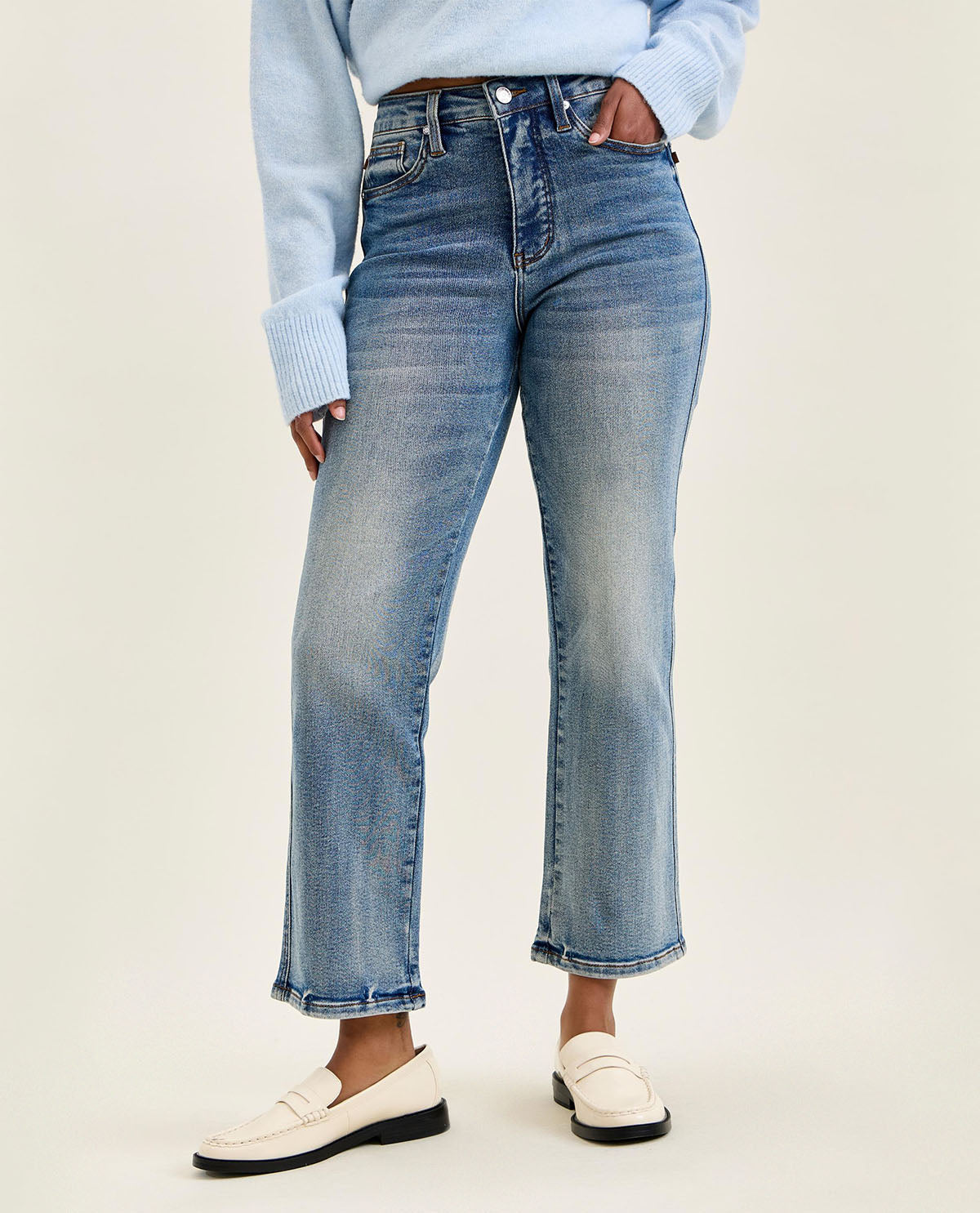 Person wearing light blue jeans and a light blue sweater on a white background