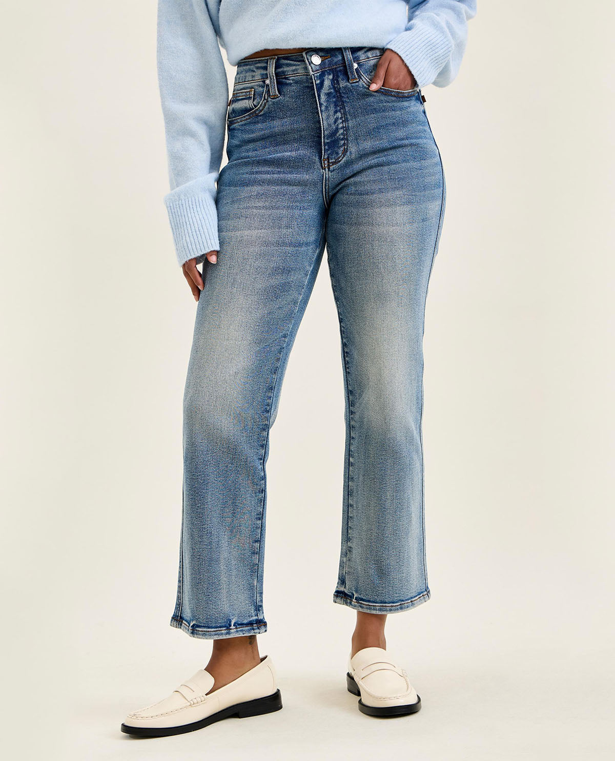 Person wearing light blue jeans and a matching sweater on a white background