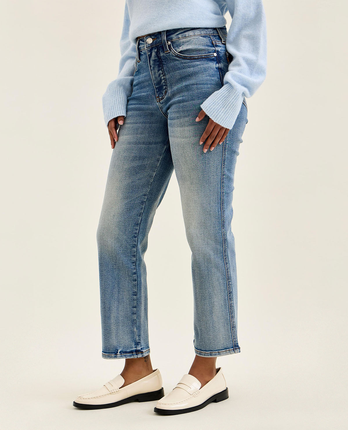 Person wearing light blue sweater and jeans on a plain background