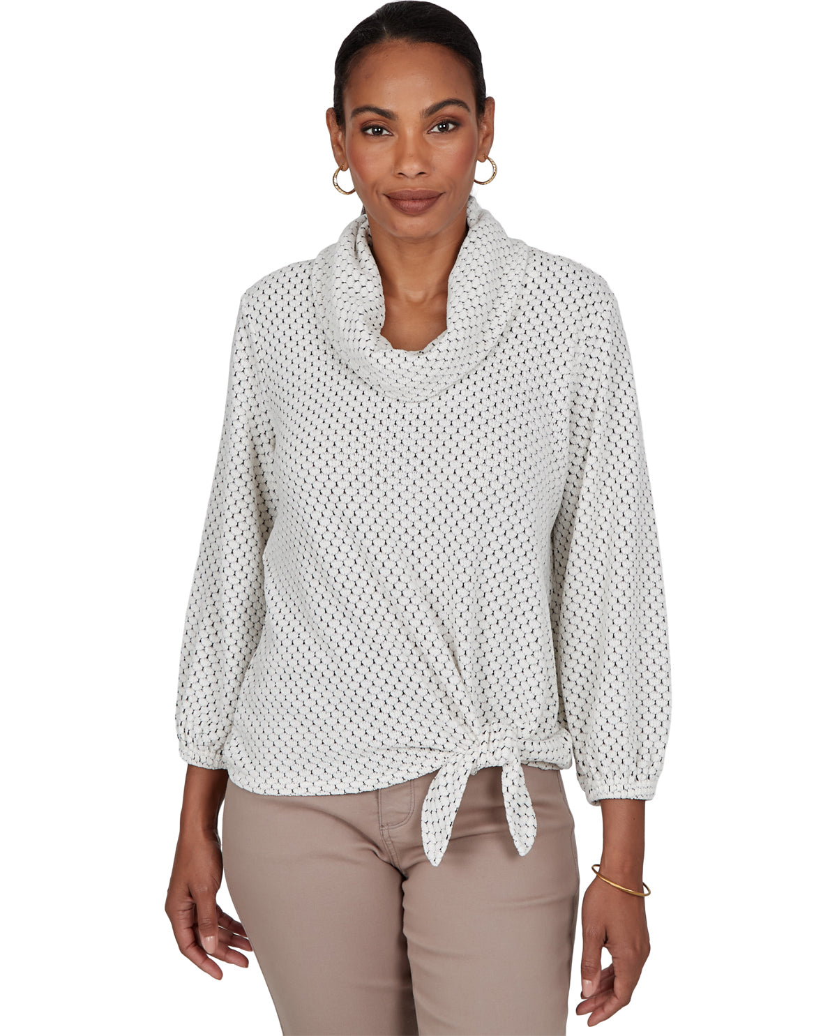 A woman modeling a white long-sleeve knit top with a cowl neck and front knot detail, paired with beige pants, against a plain white background.