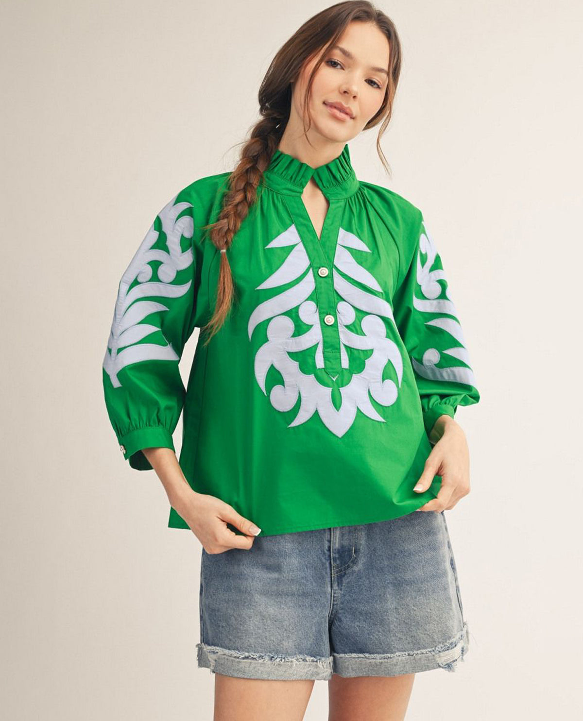 Woman wearing a green blouse with white patterns on a beige background