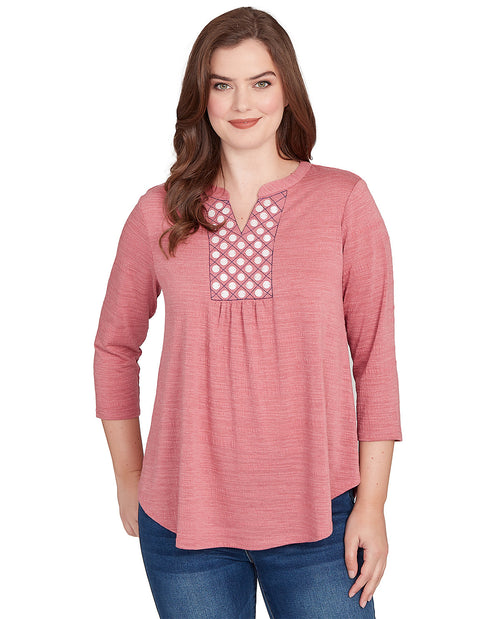 Woman wearing a pink long-sleeve top with lace detailing on a white background