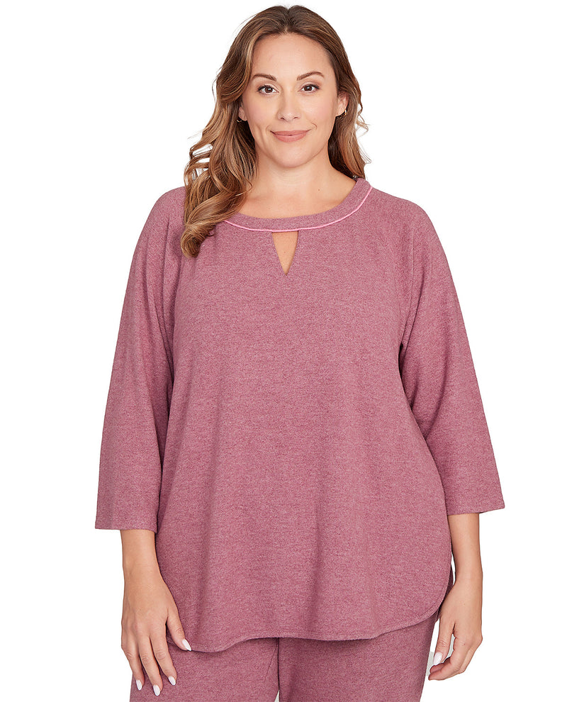 Woman wearing a mauve top with a cut-out detail on a white background