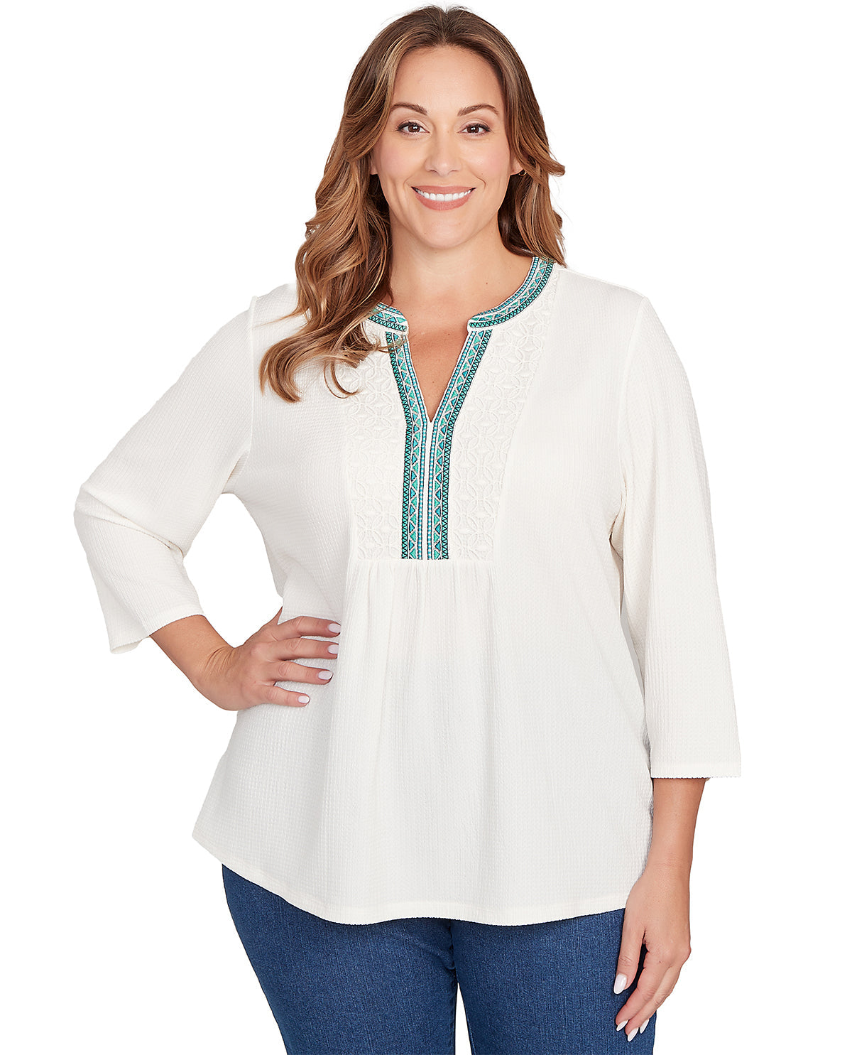 Woman wearing a white blouse with blue embroidery on a white background