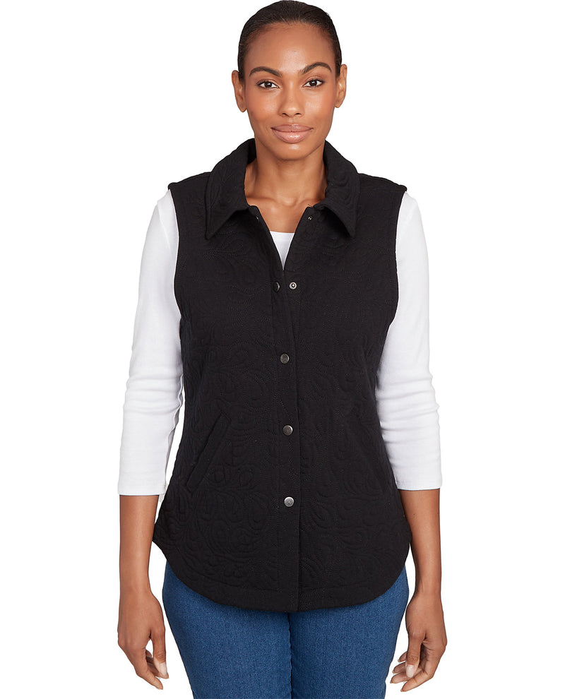 Woman wearing a black vest over a white shirt with a white background