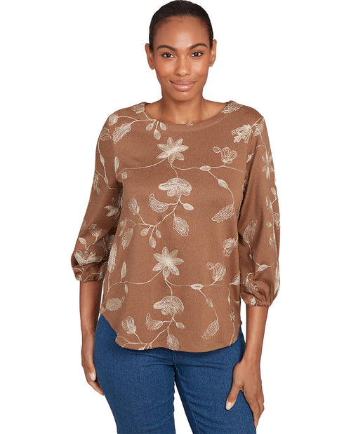 Woman wearing a brown floral blouse with blue pants on a white background