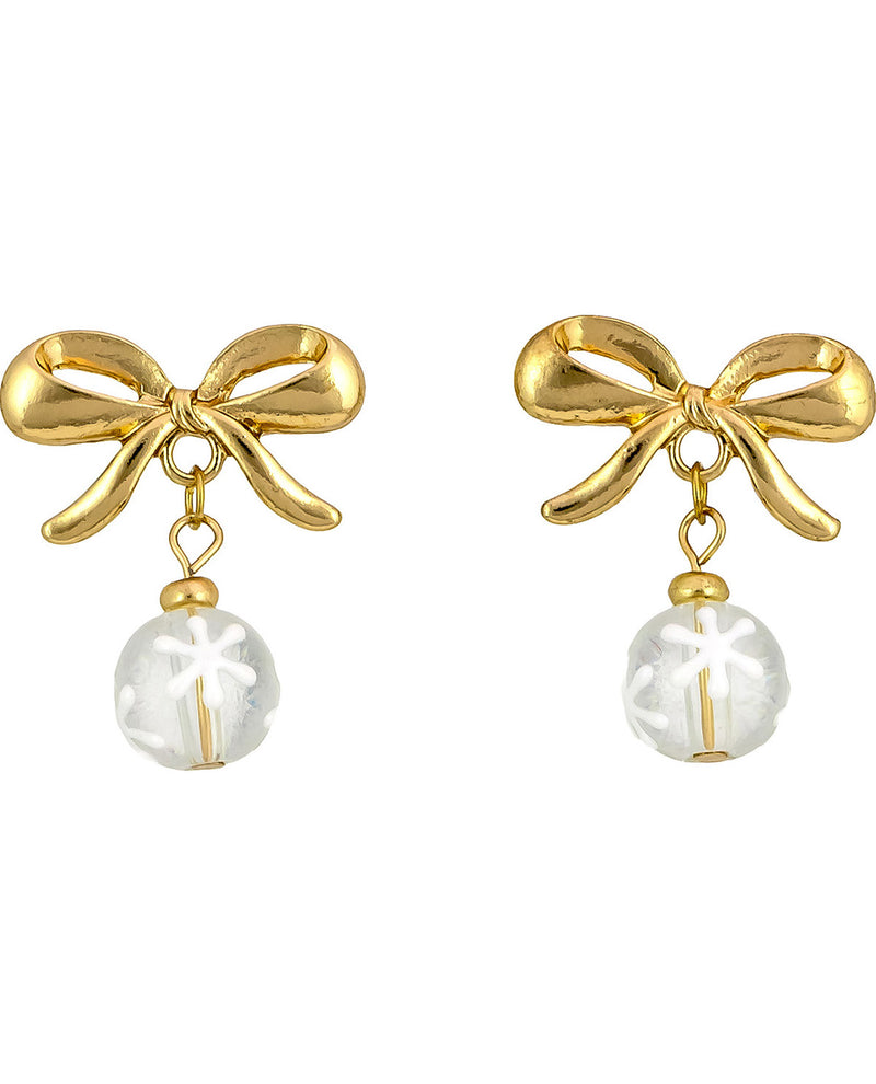 A pair of gold bow stud earrings with a dangling clear glass bead featuring a white snowflake design, set against a plain white background.