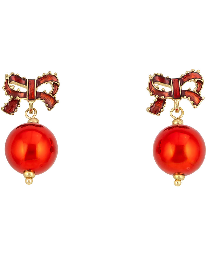 A pair of gold-tone drop earrings featuring a red enamel bow at the top and a large, glossy red pearl bead dangling below, set against a plain white background.
