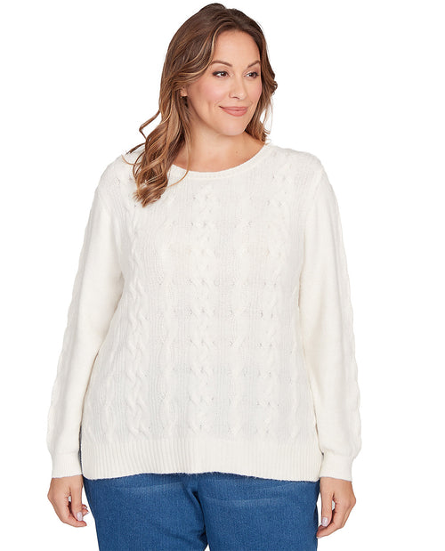 Woman wearing a white cable knit sweater and blue jeans on a white background