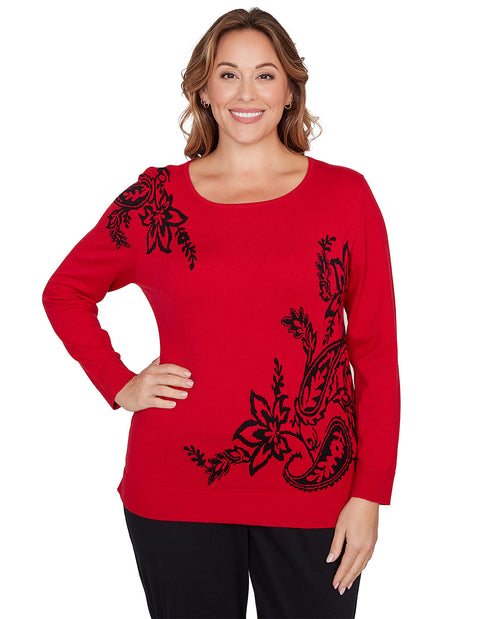 Woman wearing a red sweater with black floral patterns on a white background