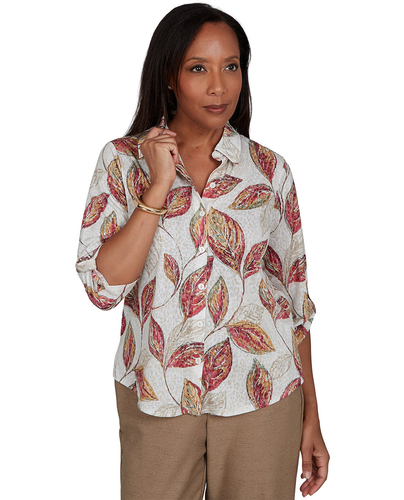 Woman wearing a patterned blouse with rolled-up sleeves on a white background