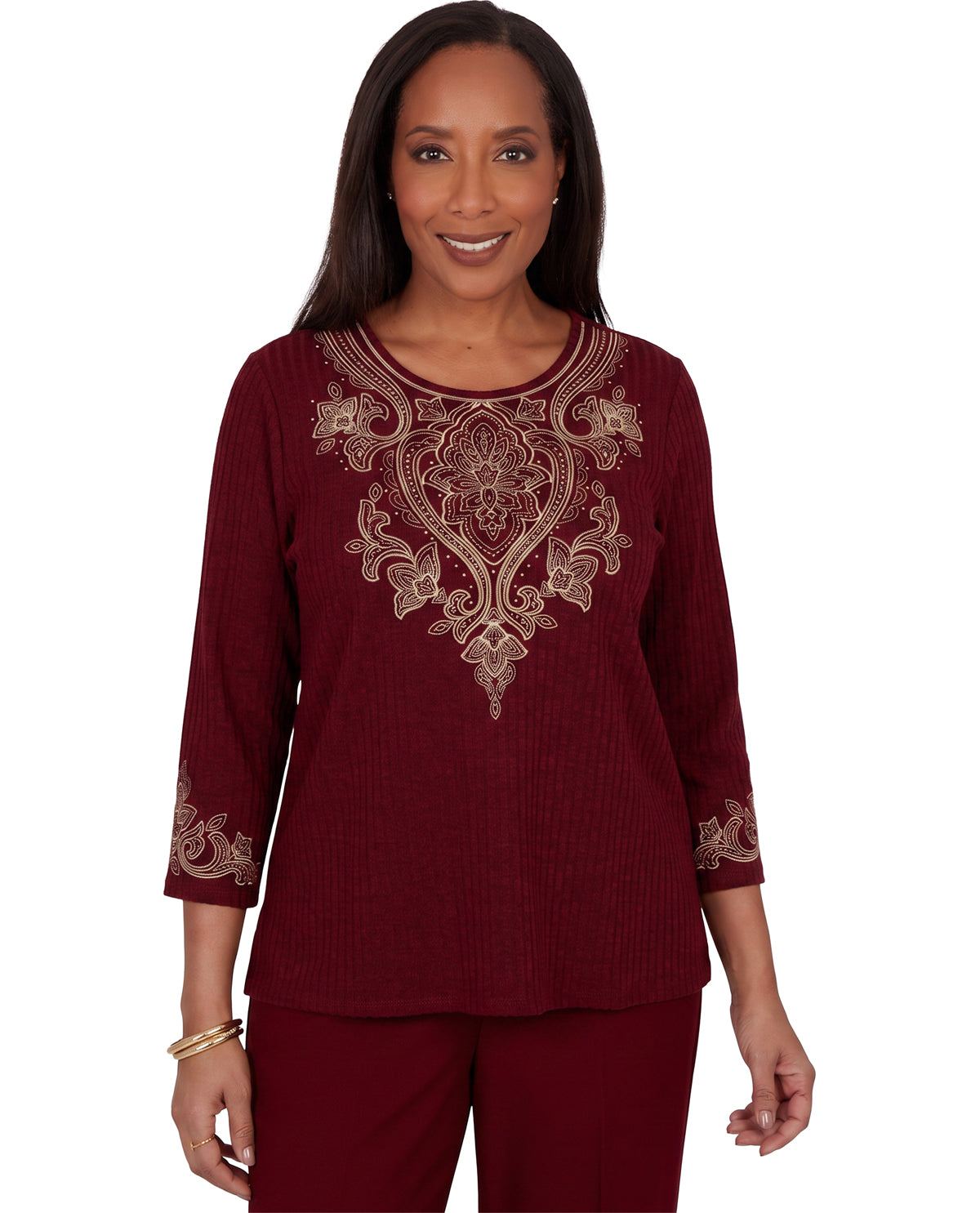 A woman modeling a ribbed maroon three-quarter sleeve top with ornate gold embroidery on the chest and cuffs, paired with matching maroon pants, against a plain white background.