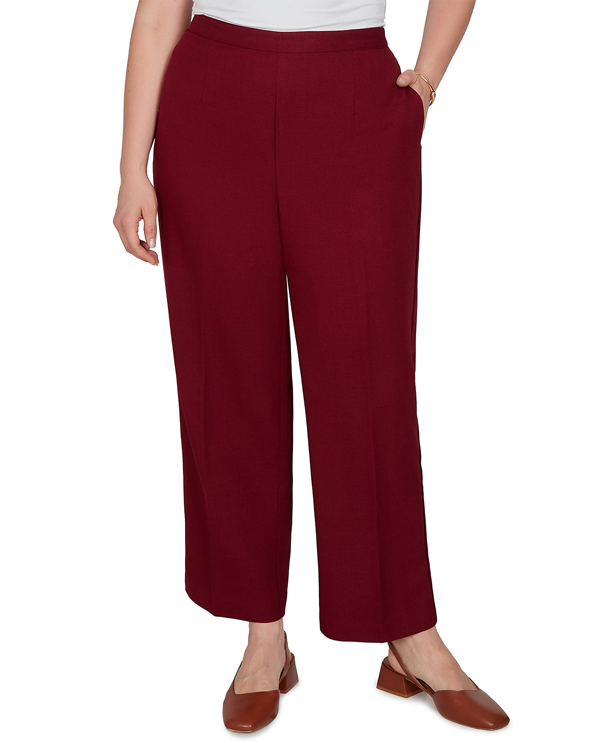 A model wearing a pair of burgundy wide-leg cropped pants with a white top and brown flat shoes, shown from the waist down on a white background.