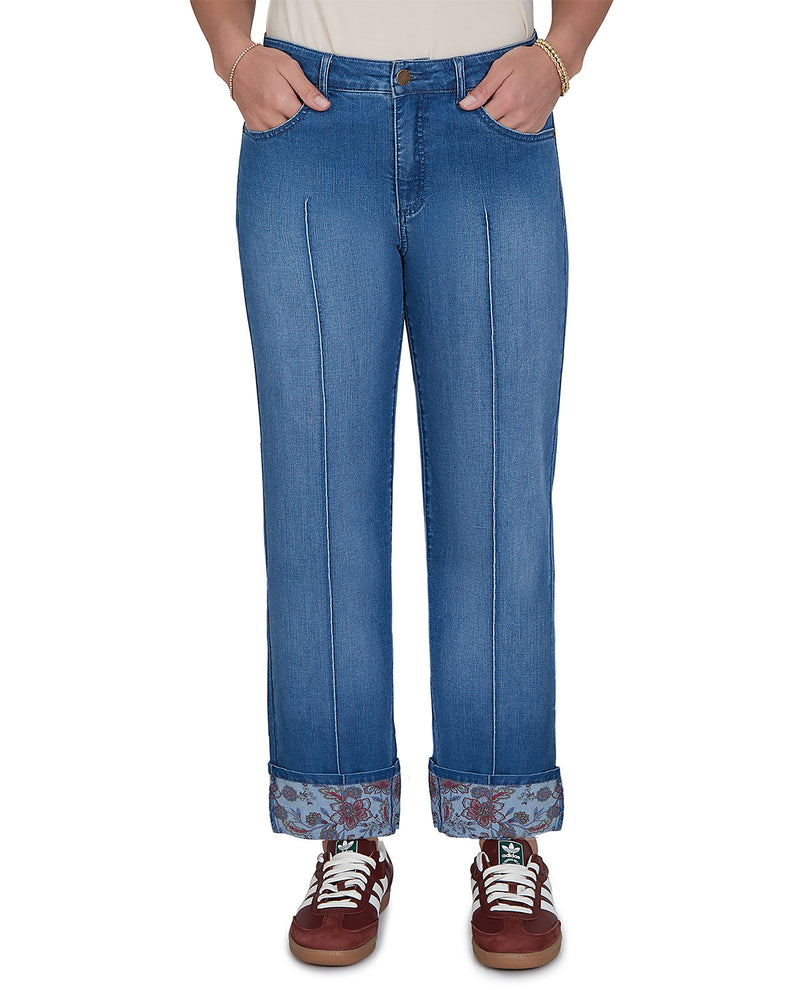 Person wearing blue jeans with rolled-up cuffs on a white background