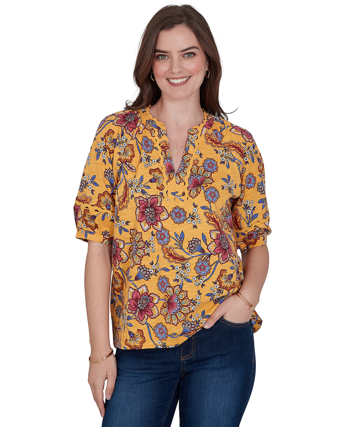 Woman wearing a yellow floral blouse with blue jeans on a white background